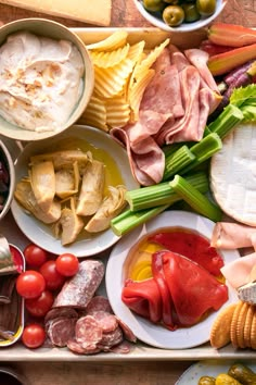 an assortment of food is laid out on a table with cheese, crackers and olives