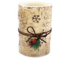 a candle holder made out of birch tree trunks with holly and berries tied around it