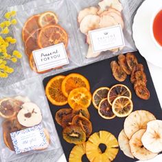 orange slices and dried fruit on a tray next to a cup of tea