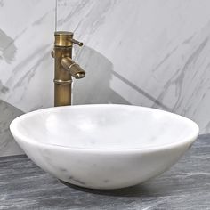 a white bowl sink sitting on top of a counter next to a faucet