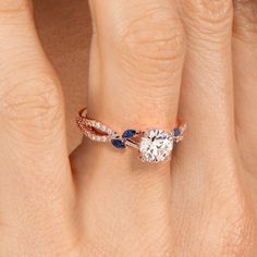 a woman's hand with a diamond and blue sapphire engagement ring on her finger