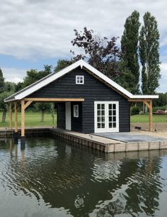 a boathouse sits on the water in front of a dock with a wooden platform