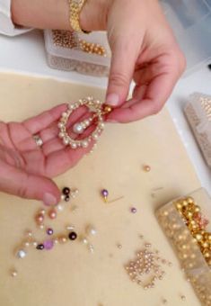 a person is making jewelry with gold and pearls