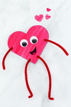 a paper heart with eyes and arms on a marble surface