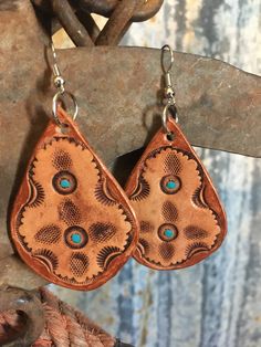 "Stamped leather earrings. Each earring is stamped by hand then hand painted with turquoise and bronze accents. This set is bold as well as lightweight. Leather piece approx: 2\" x 1.25\" Tag us on Instagram @doubleAconnected to be featured! All items produced by Double A Connected Leatherworks are handmade, many to-order. In working with leather there will be slight variations from item to item--these are not flaws. These are truly one of a kind, handmade items not produced on a large scale." Brown Stamped Copper Jewelry, Artisan Stamped Brown Jewelry, Handmade Leather Turquoise Earrings, Handmade Leather Earrings In Turquoise, Handmade Turquoise Leather Earrings, Brown Bohemian Concho Earrings, Bohemian Turquoise Leather Earrings, Artisan Hand-tooled Teardrop Earrings, Hand Tooled Teardrop Bohemian Earrings