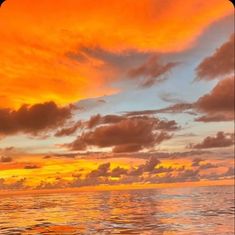 an orange and blue sunset over the ocean with clouds in the sky as seen from a boat