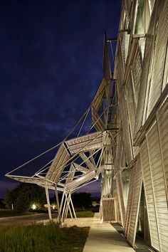 a building that has some kind of structure on it's side and is lit up at night