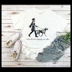 A comfortable unisex t-shirt featuring a print of a lady walking her labrador with the text 'And she lived happily ever after'. This t-shirt provides a relaxed, neat look that can blend into any occasion, casual or semi-formal, giving off a warm and cozy vibe. Perfect for dog lovers, fairytale enthusiasts, and those looking for a unique and heartwarming design. Ideal for everyday wear, as a gift for loved ones, or for special occasions like birthdays and holidays. Product features - Shoulder tap Shoulder Tap, Lady Walking, Dog Lover Shirt, Cute Pet, Live Happy, Pet Owner, Look Plus, Animal Lovers, Happily Ever After