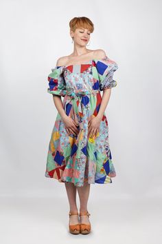 a woman wearing a colorful dress with an off the shoulder neckline and ruffled sleeves