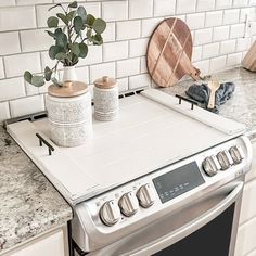 a stove top oven sitting in a kitchen next to a potted plant and cutting board