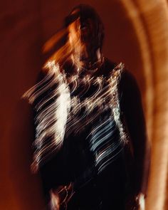 a blurry photo of a man standing in front of a wall with his hand on his hip