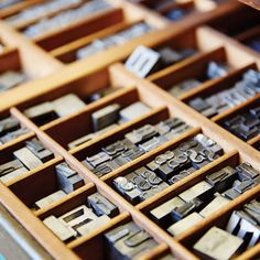 an assortment of metal letters and numbers in a drawer with wooden trays filled with them