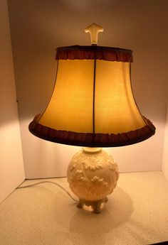 a lamp that is sitting on top of a table next to a white vase with a brown shade