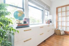 a living room with wooden floors and white furniture, including a globe on the window sill