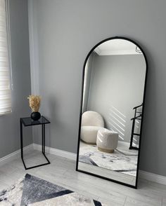 a mirror sitting on top of a white floor next to a table and chair in a room