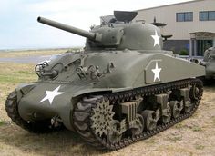 two army tanks are parked in front of a building with white stars on the side