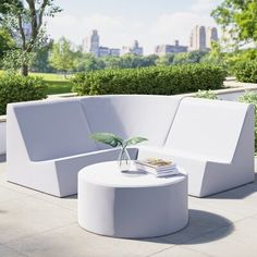 a white couch sitting on top of a cement floor next to a lush green park