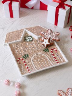 a gingerbread house decorated with icing and candy canes next to some christmas decorations