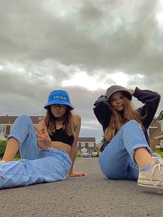 two young women sitting on the ground with their feet up and one holding her hand out