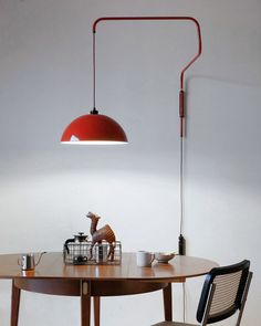 a table with two chairs and a lamp on the wall above it in a white room