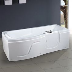 a white bath tub sitting on top of a tiled floor next to a wall and window