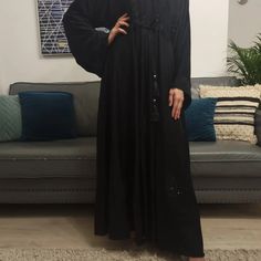 A premium addition, the Black Umbrella Abaya with a combination of applique and stoneworks, made with premium quality nida. Perfect for occasions all year round. Its inner tassel belt can be adjustable to get a more desired look. Suitable for special occasions like Eid/Ramadan Parties. Closed Abaya Fabric: 100% Nida ( Soft & Lightweight) Beautiful flow gives an elegant look Embroidery details on sleeves, chest, and lower panel of the abaya. Hijab: Included Belt: Tassel, included The model is a U Modest Black Kaftan For Eid, Embellished Maxi Abaya For Eid, Eid Embellished Maxi Abaya, Embellished Maxi Length Abaya For Eid, Black Maxi Length Thobe For Eid, Black Maxi Length Kaftan With Dabka, Black Maxi Abaya For Eid, Black Embroidered Floor-length Abaya, Black Maxi Length Abaya For Eid