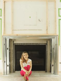 a woman sitting on the floor in front of a fire place