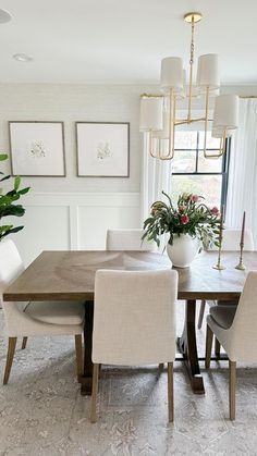 a dining room table with white chairs and a potted plant in the middle of it