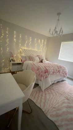 a bedroom decorated in pink and white with lights on the headboard, bed, desk and chair