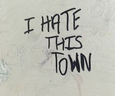 i hate this town written on the side of a white wall with black writing that says, i hate this town