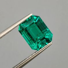 an emerald is being held by a pair of tongs