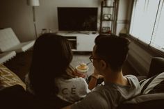 a man and woman sitting on a couch watching tv