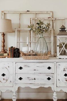 an old white dresser with flowers in a vase on top and other items around it