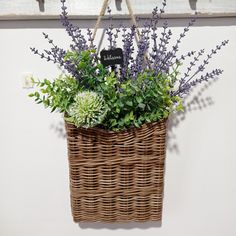 a wicker basket hanging on the wall with flowers in it