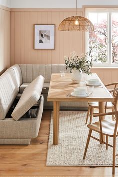 a living room filled with furniture and a wooden dining table surrounded by white rugs