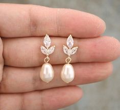 a pair of white pearls and crystal leaves are on the finger of a woman's hand