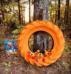 an orange wreath sitting next to a tree in the woods