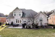 a large brick house sitting on top of a lush green field