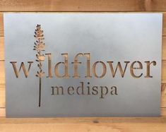 a metal sign that says wildflower medispa on the side of a wooden wall