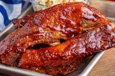 ribs covered in bbq sauce sitting on a tray next to a bowl of popcorn