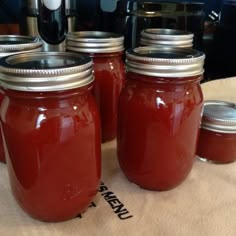 four jars filled with red liquid sitting on top of a table