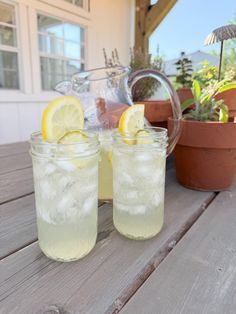 two glasses filled with lemonade sitting on top of a wooden table