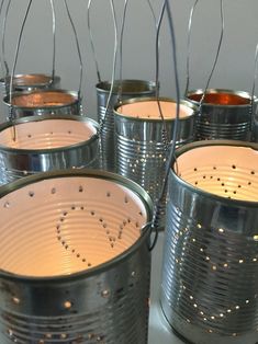 several tin cans with holes in them sitting on a counter top next to some candles