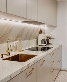 a kitchen with marble counter tops and gold pulls on the faucet above the sink