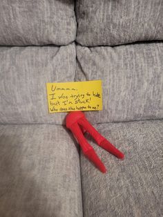 a red pair of scissors sitting on top of a couch with a note attached to it