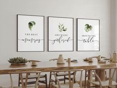 three framed art prints on the wall above a dining room table with chairs and potted succulents