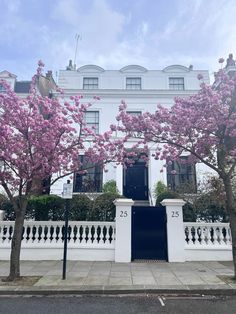 a large white house with pink flowers on the trees