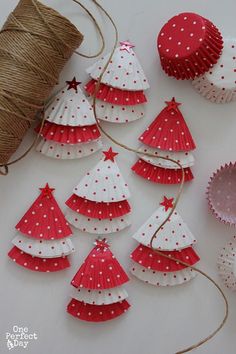 red and white christmas tree decorations with twine spools on the table next to it