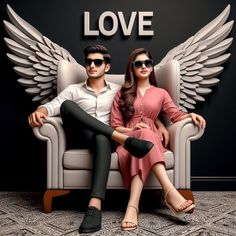 a man and woman sitting on a white chair with wings over their heads, in front of a black background