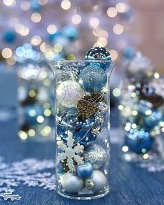 a glass vase filled with ornaments on top of a blue table covered in snowflakes